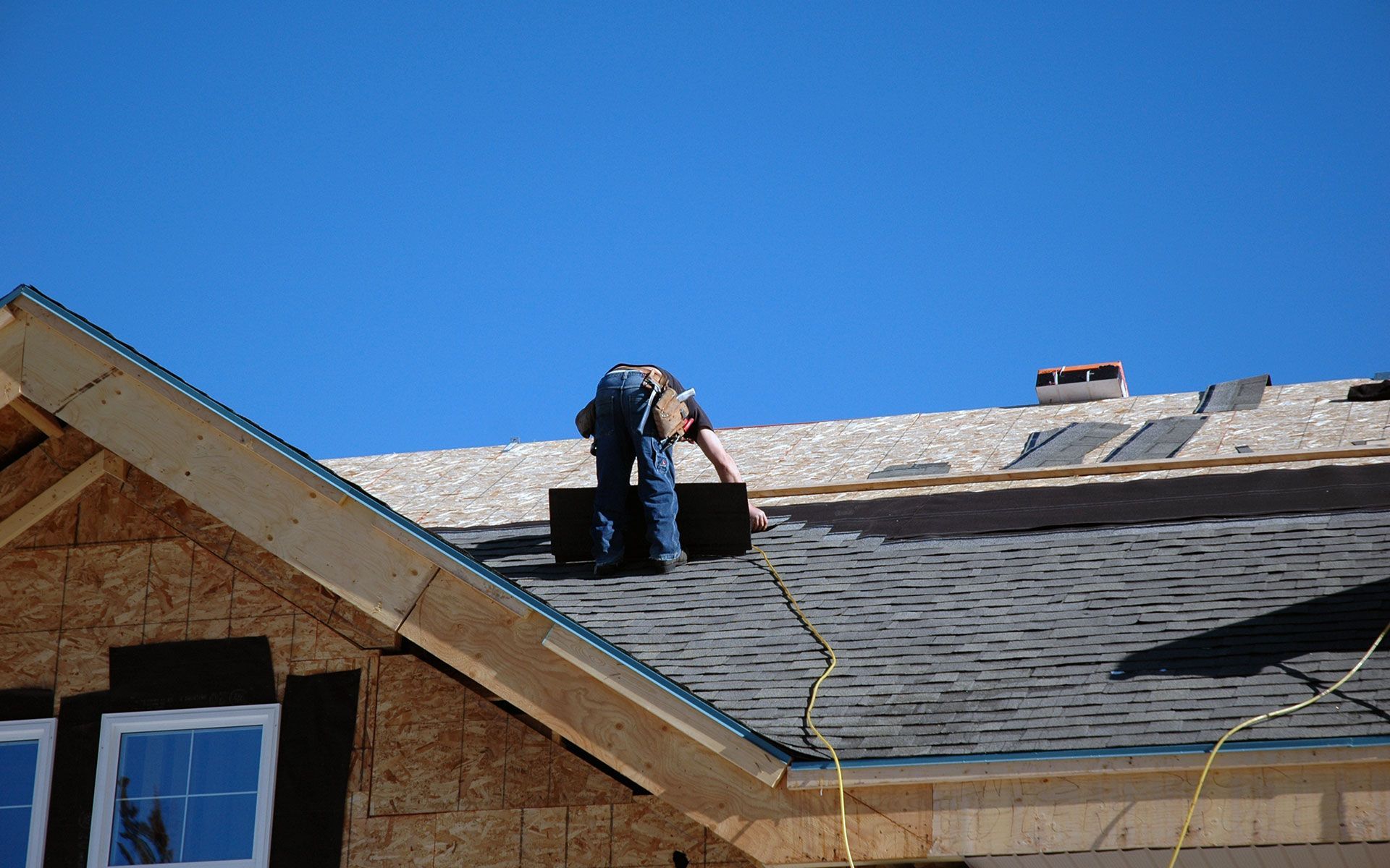 A man is working on the roof of a house.