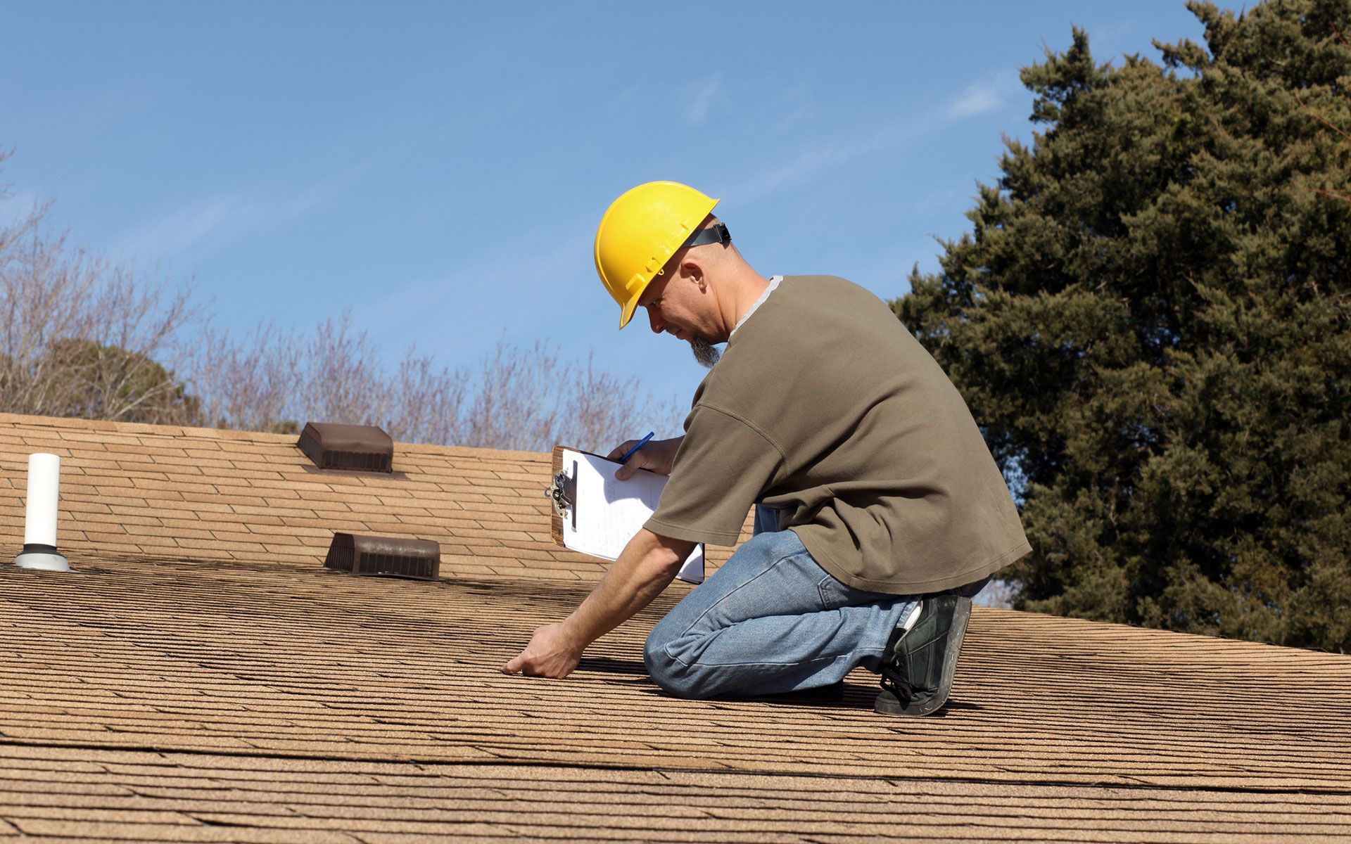 A man wearing a hard hat is working on a roof