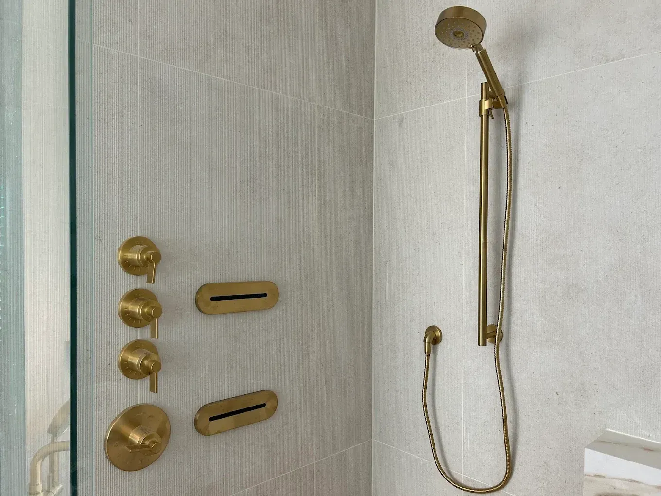 A bathroom with a brass shower head and faucets