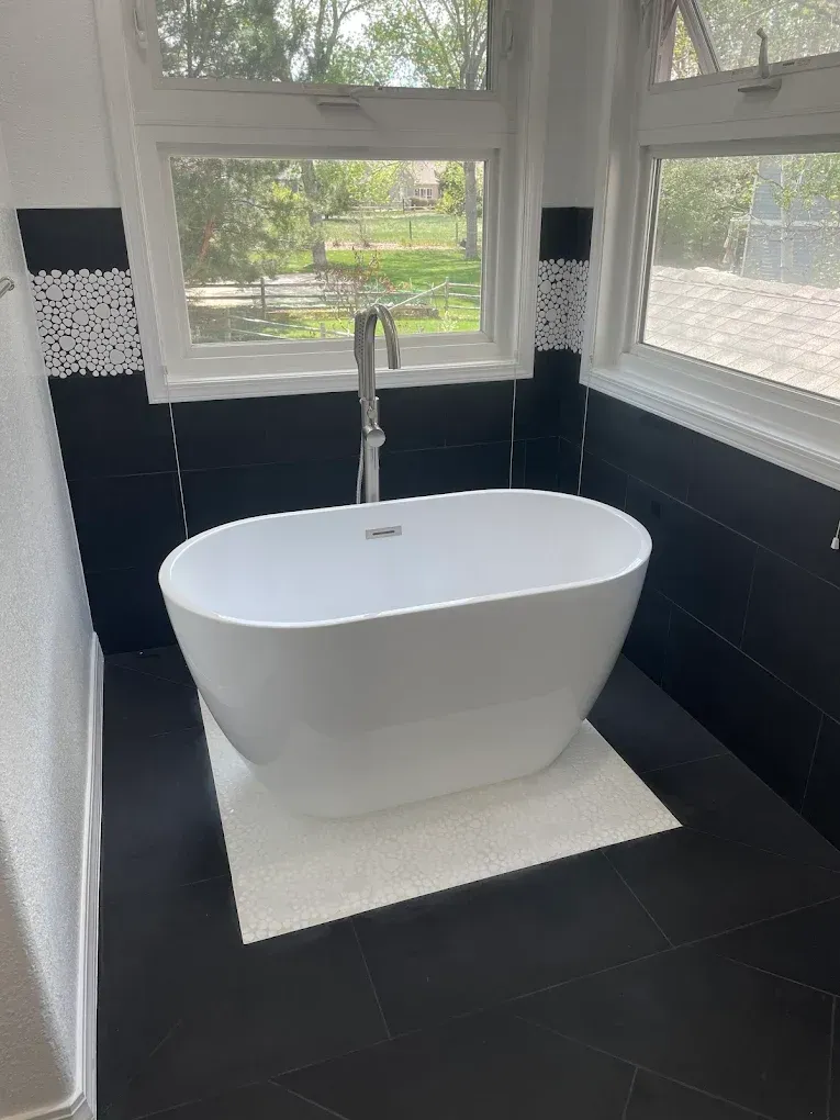 A white bathtub is sitting in a bathroom next to a window.