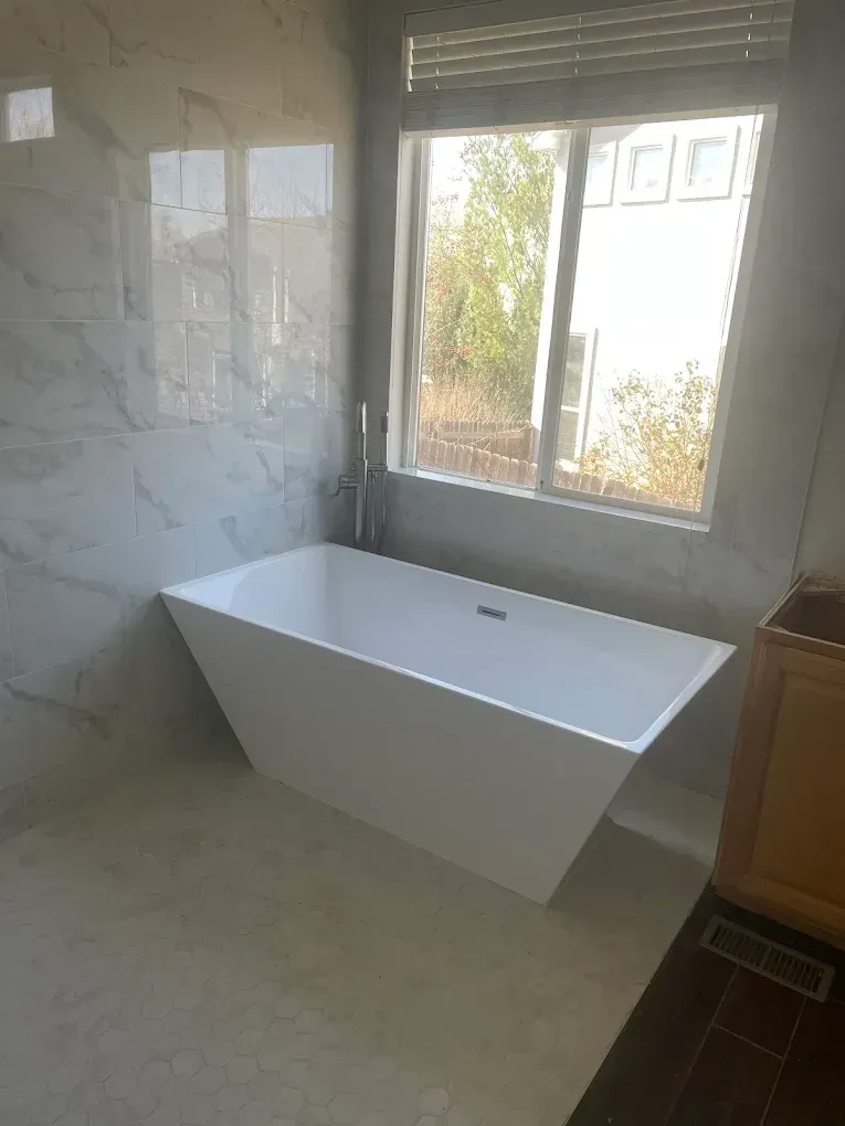 A white bathtub is sitting in a bathroom next to a window.