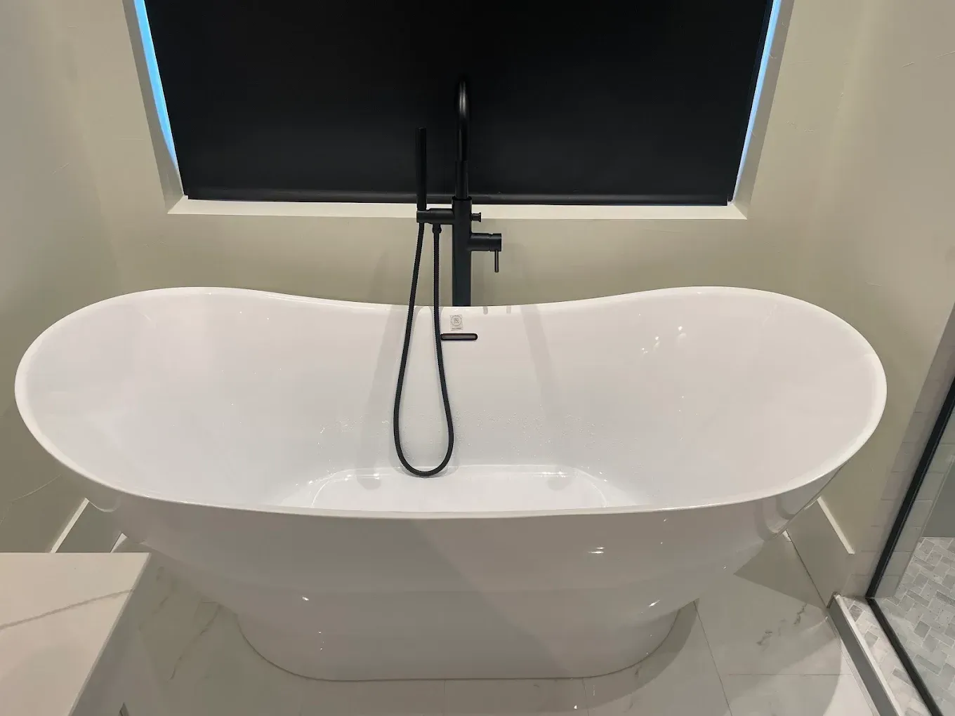 A white bathtub with a black faucet in a bathroom.