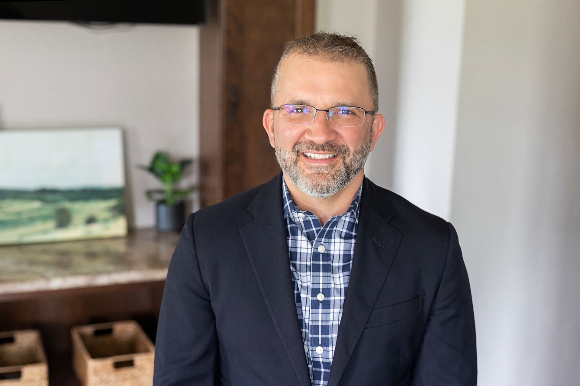 A man in a suit and plaid shirt is smiling for the camera.