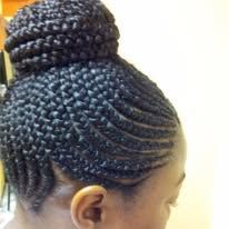 Braided dark hair styled in a bun, with the braids following a curved pattern on the head.