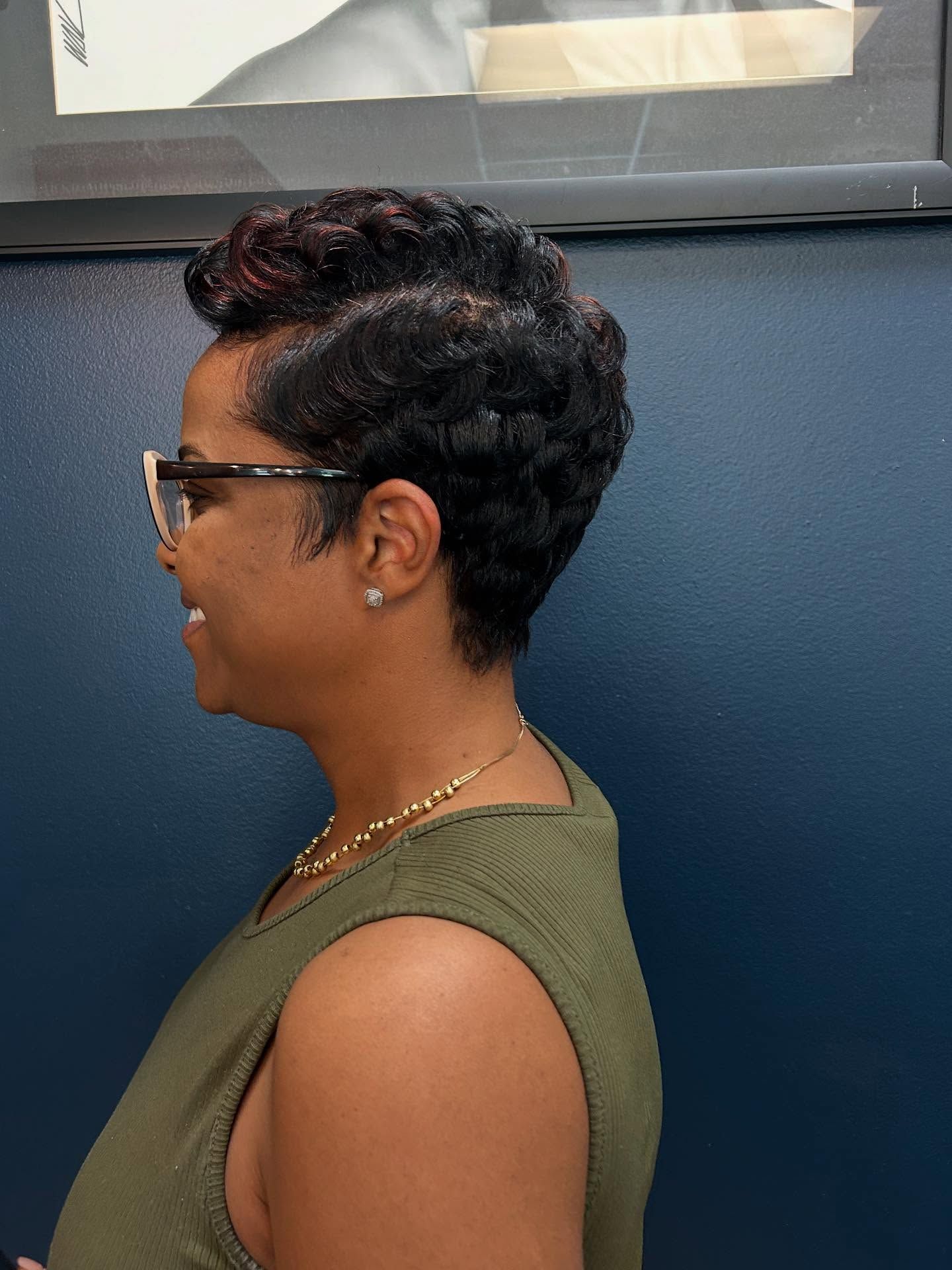 Woman with curly black hair in a salon, smiling.