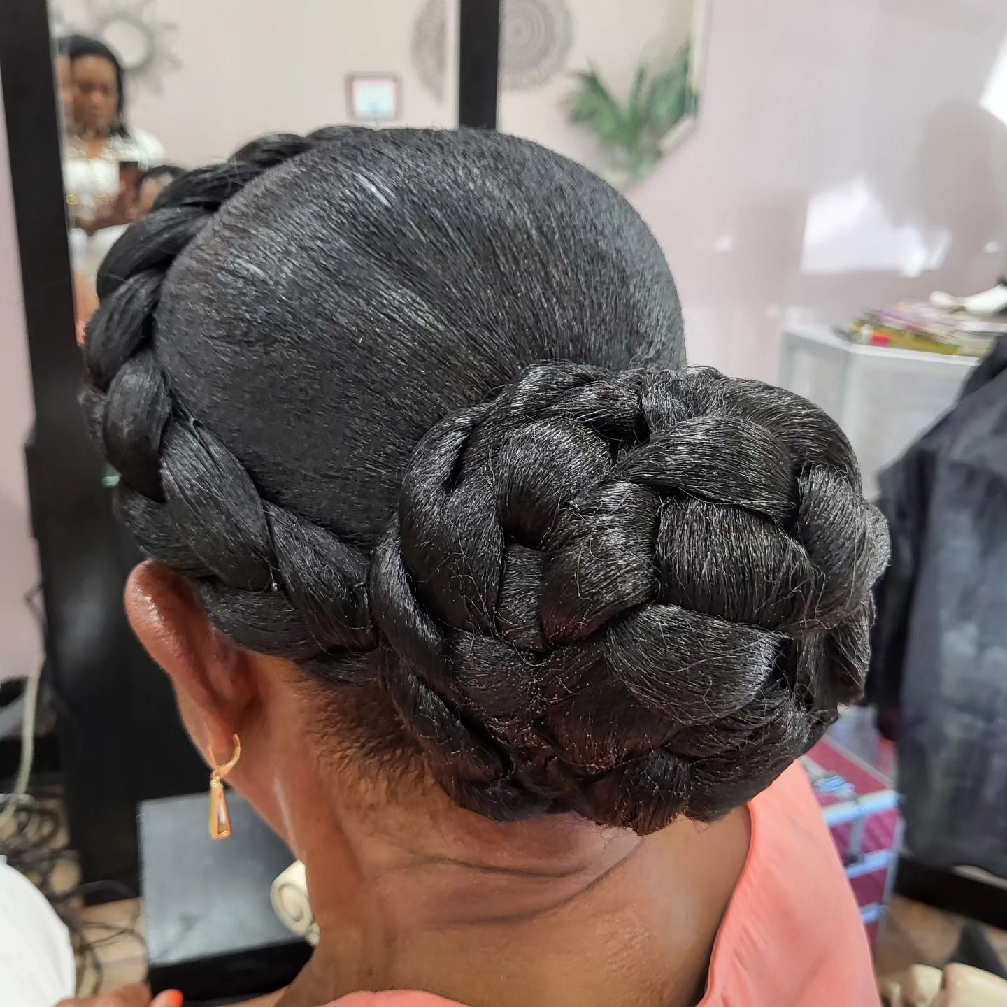 Woman with braided hairstyle, dark hair, and low bun in a salon setting.