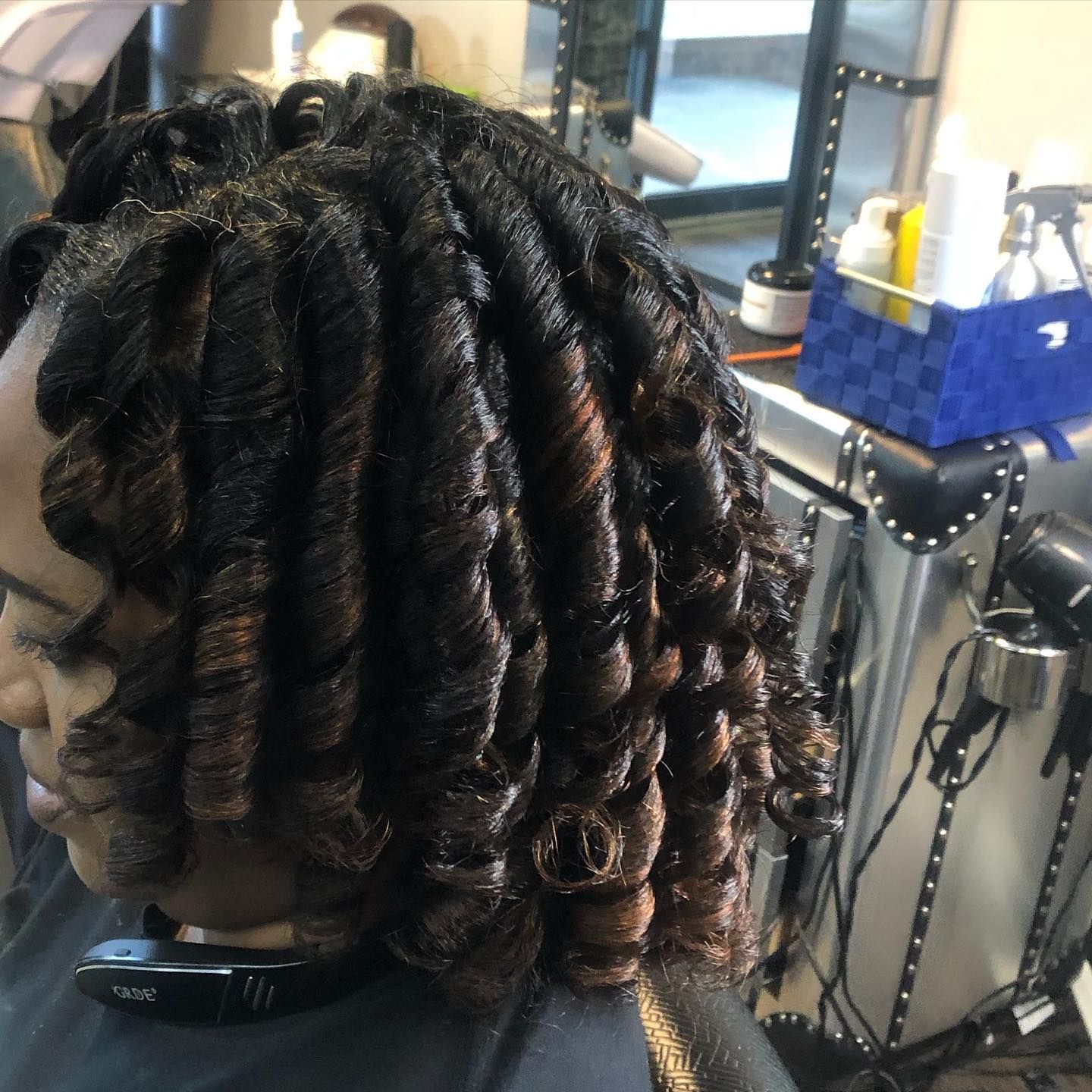 Woman with dark, tightly curled hair styled in a salon.