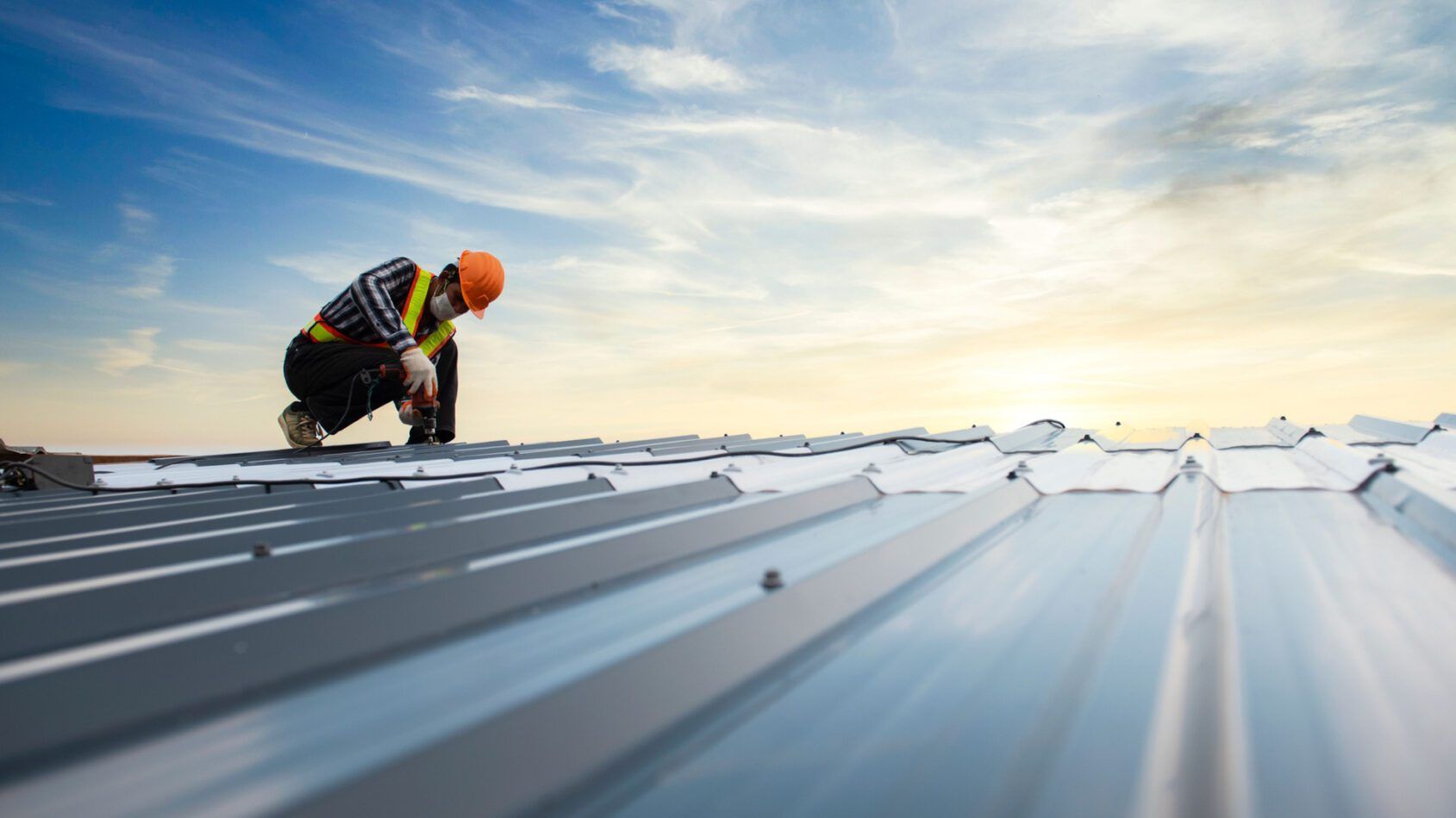 A construction worker is working on a metal roof.