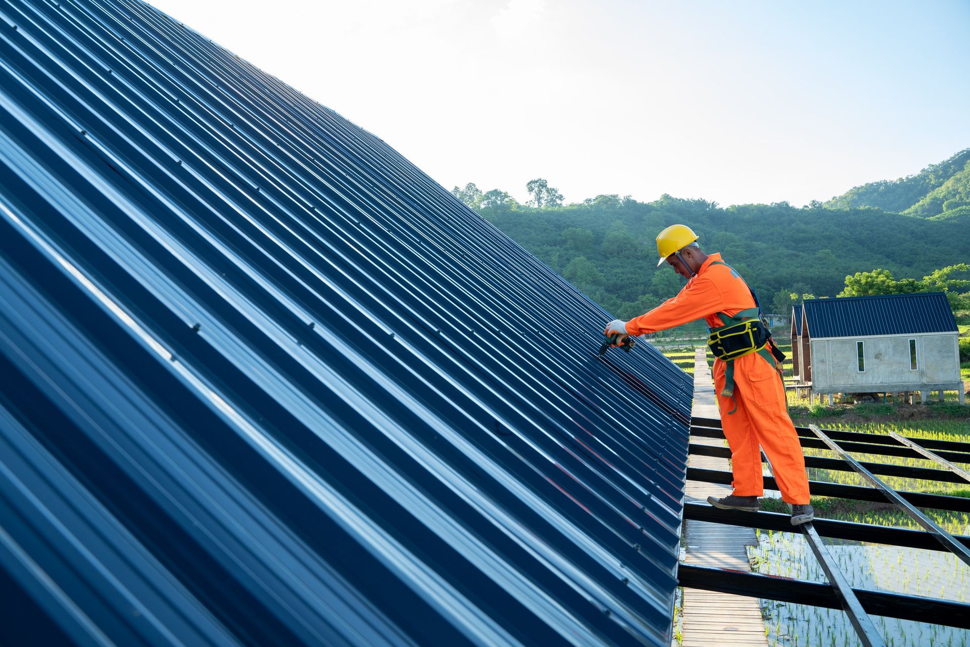 A man is working on a blue metal roof.