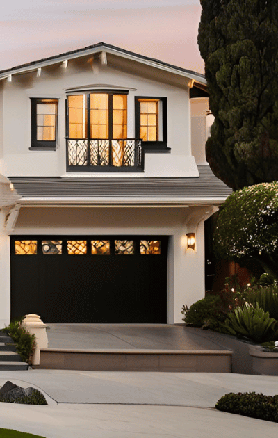 A white house with a black garage door and a balcony
