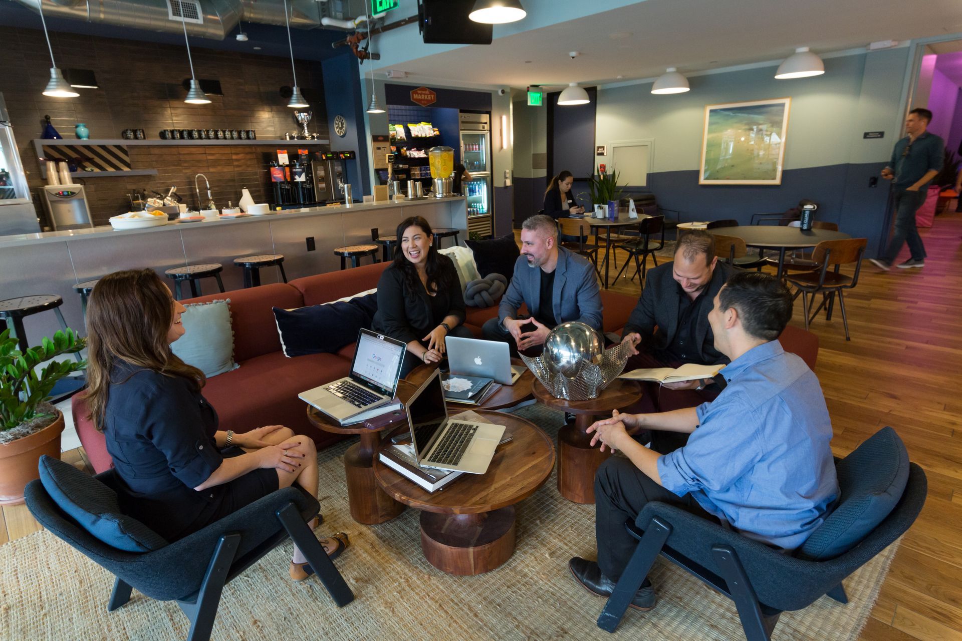 A group of people are sitting around a table with laptops.