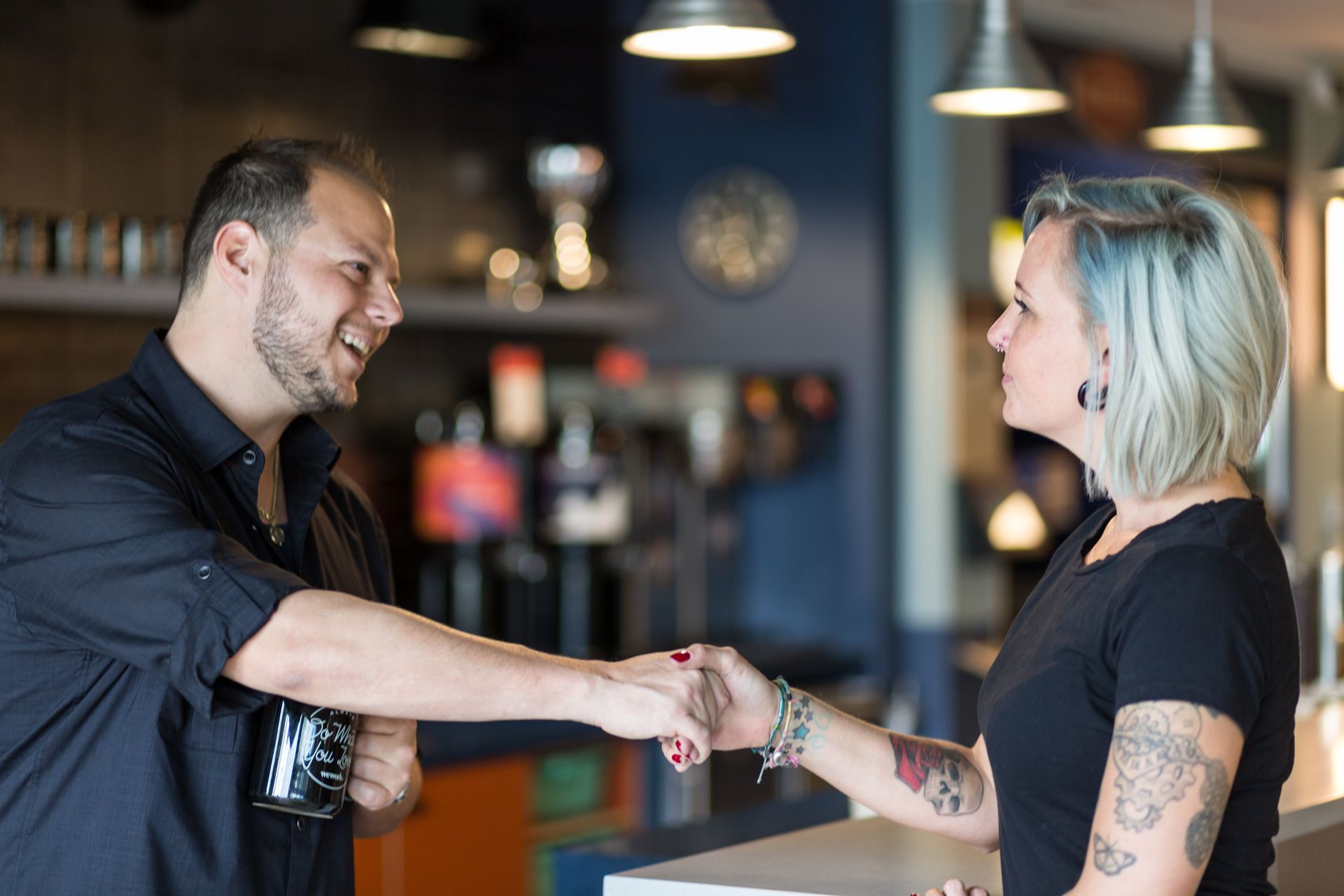 A man and a woman are shaking hands in a restaurant.