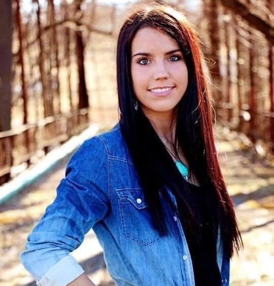The woman is wearing a denim jacket and smiling for the camera.