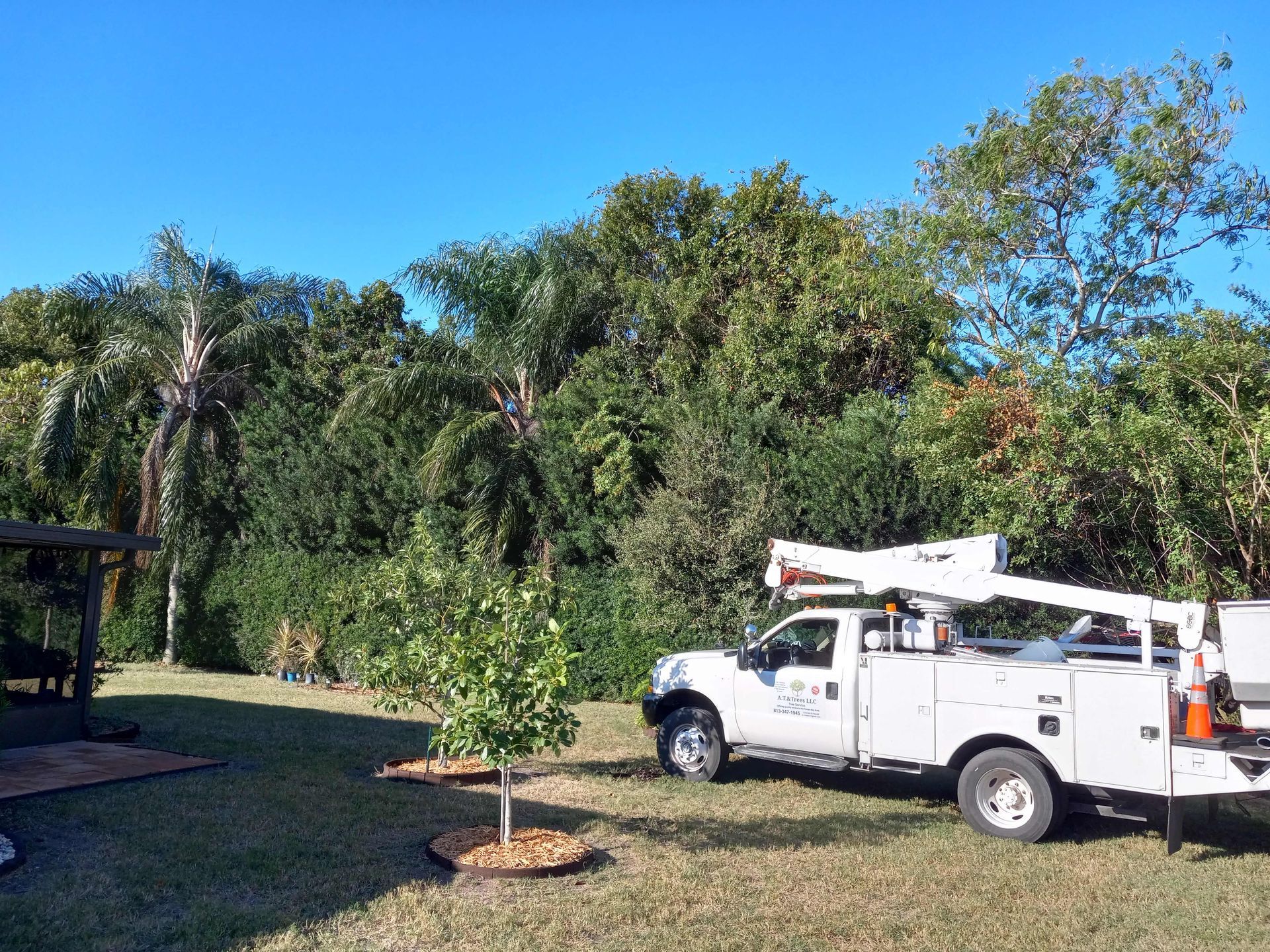 A white truck with a crane on the back is parked in a grassy field.