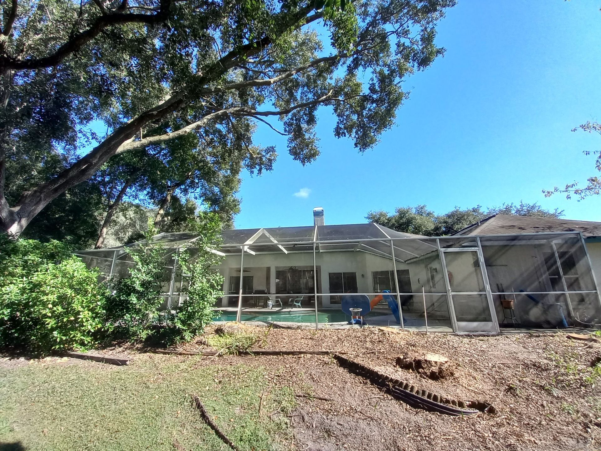 A house with a screened in porch and a tree in front of it