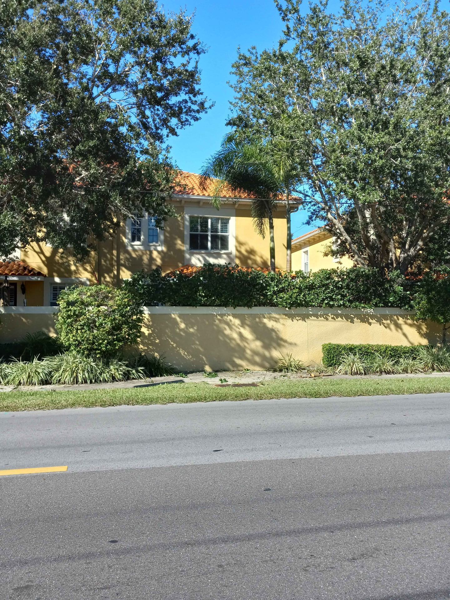 A yellow house sits on the side of a road surrounded by trees