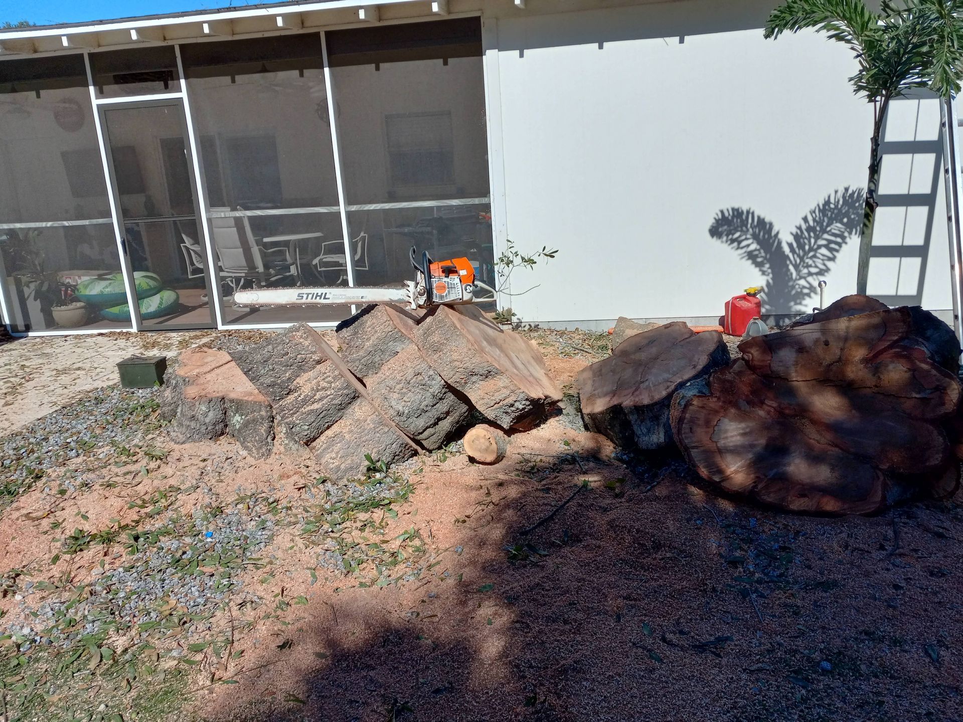 A pile of logs is sitting in front of a screened in porch.
