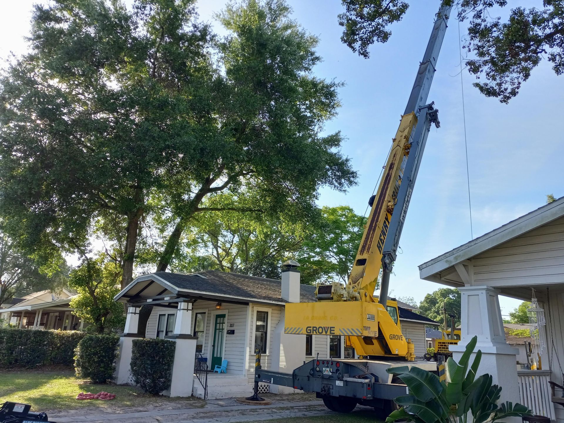 A yellow crane is sitting in front of a house.