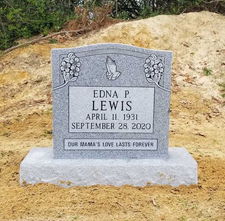 a gravestone for edna p. lewis is sitting on top of a dirt hill .