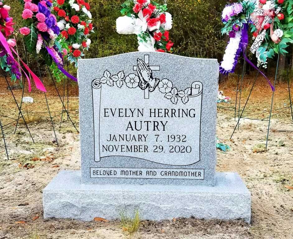 a gravestone for evelyn herring autry is surrounded by flowers .