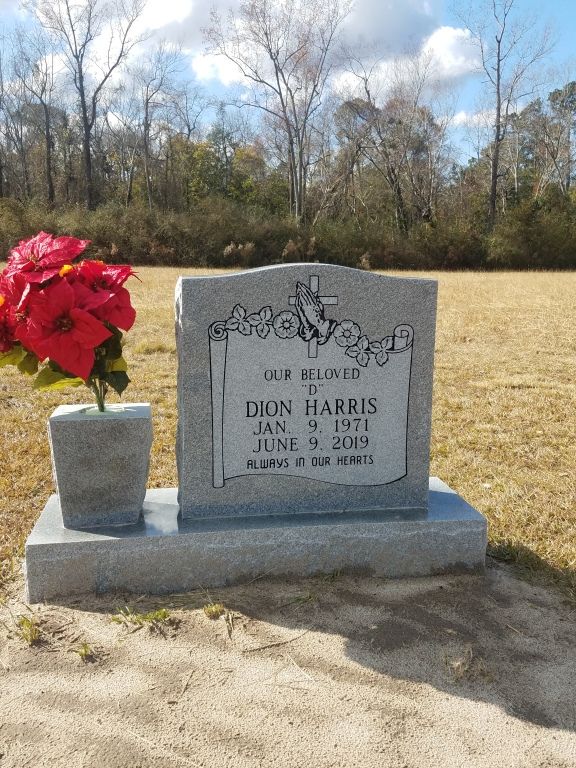 a gravestone with a vase of red flowers on it