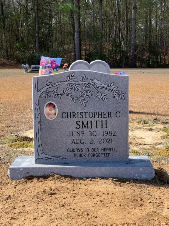 a gravestone for christopher c. smith is sitting in the dirt in a cemetery .
