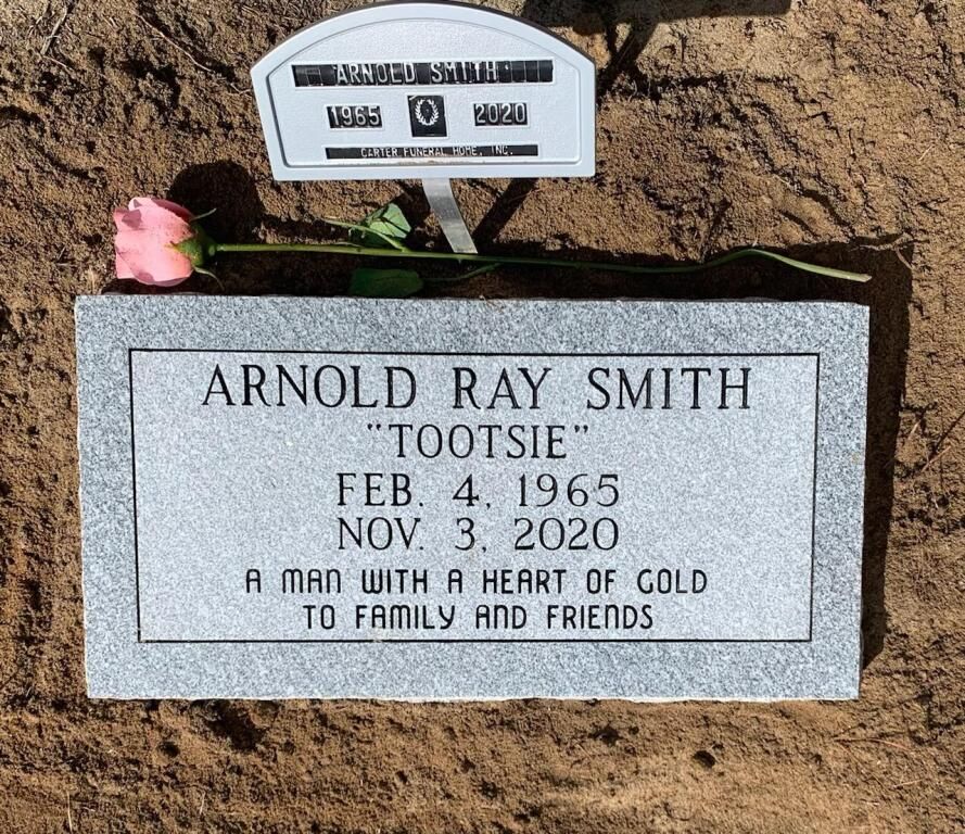 a gravestone for arnold ray smith with a pink rose on top