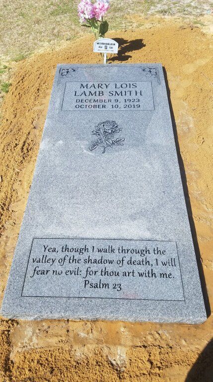a grave in a cemetery with a bible verse on it .