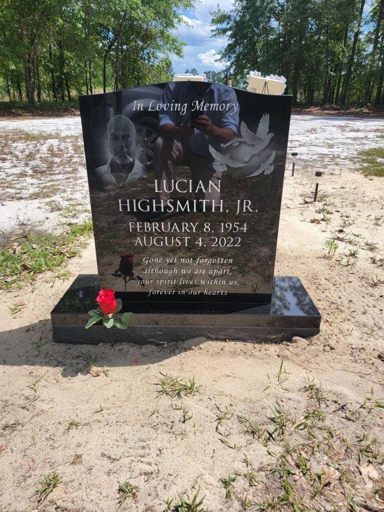 a black gravestone with a red rose on it in a graveyard .