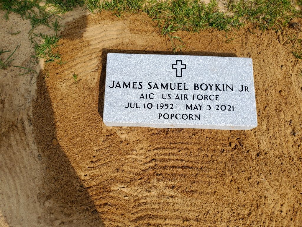 a gravestone for james samuel boykin jr. is sitting in the dirt .