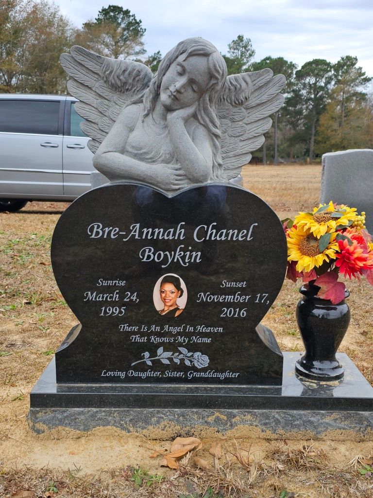 a black heart shaped gravestone with a statue of an angel on it .