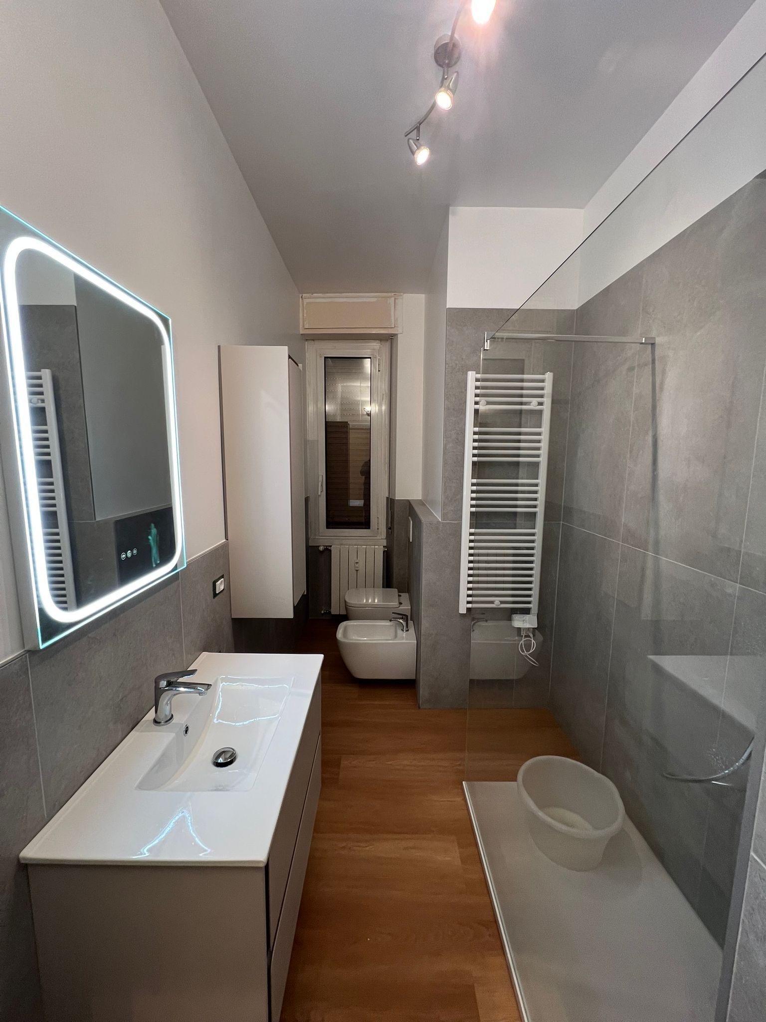 Stanza vuota con grandi porte a vetri che si affacciano su un lago e sugli alberi. 