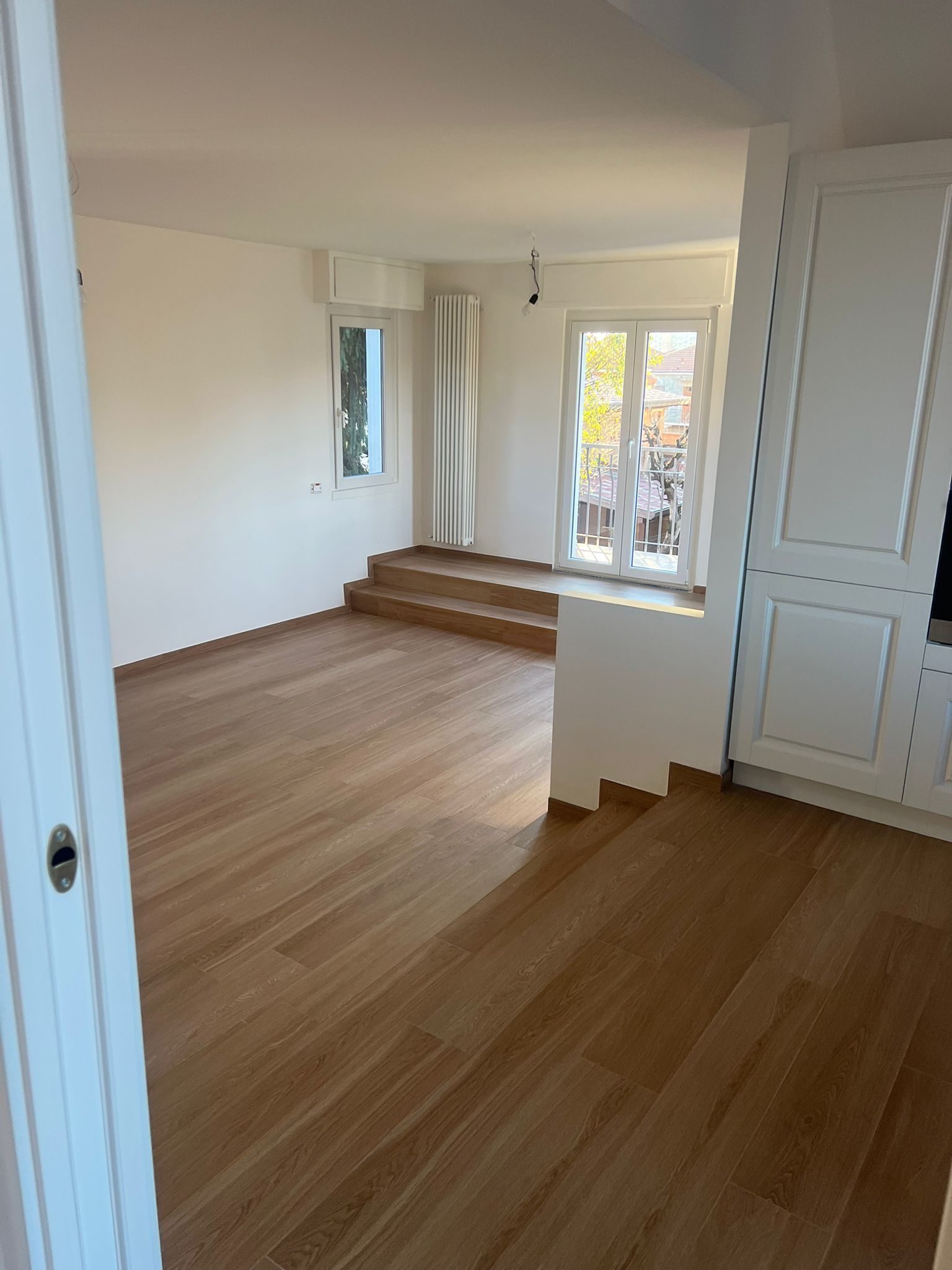 Camera moderna con ampie finestre che si affacciano sul verde paesaggio. Piante e opere d'arte decorano l'ambiente.