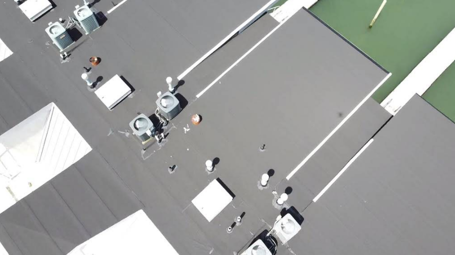 Aerial view of a flat roof with HVAC units, vents, and white stripes.