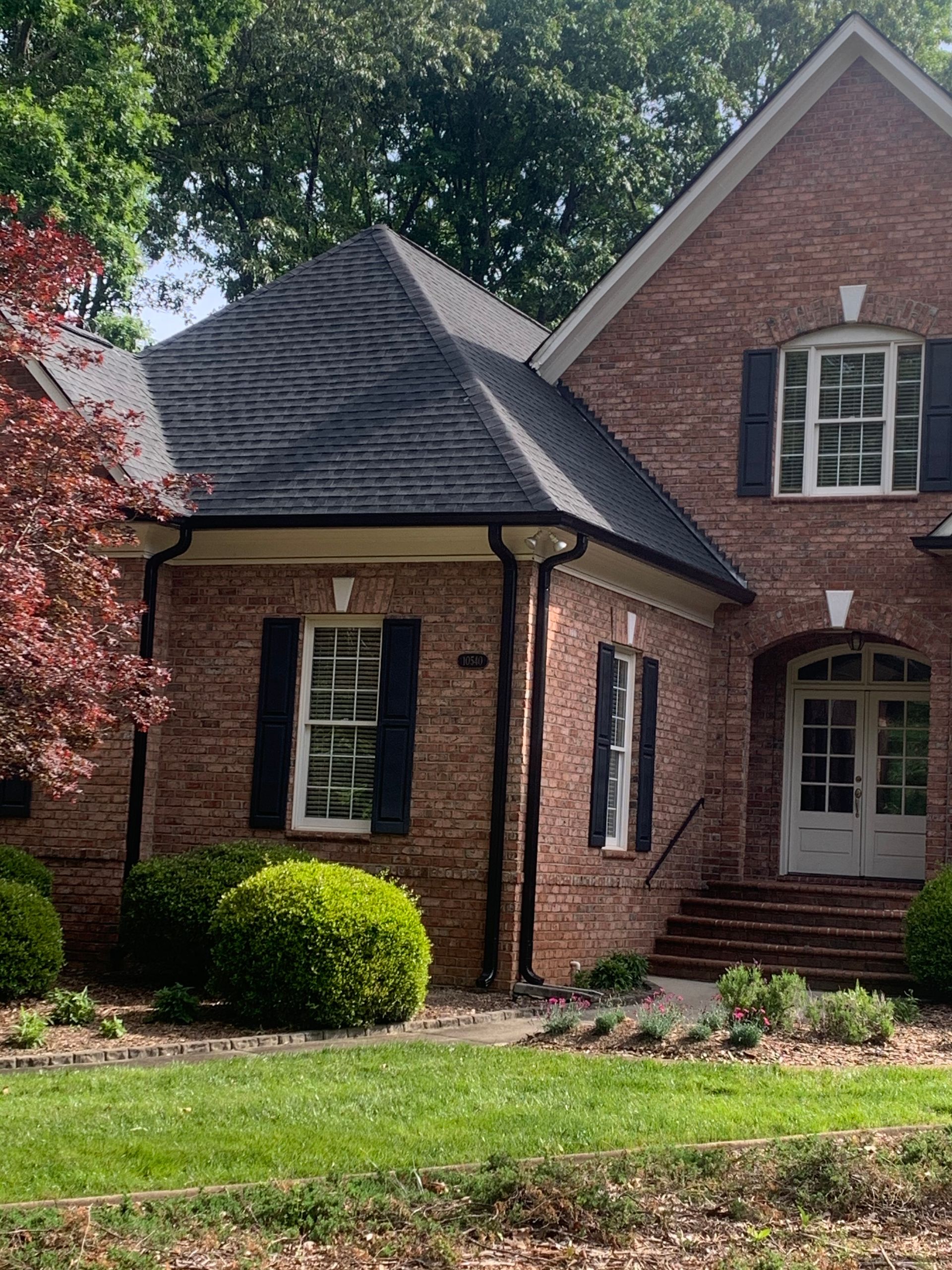 A large brick house with black shutters on the windows