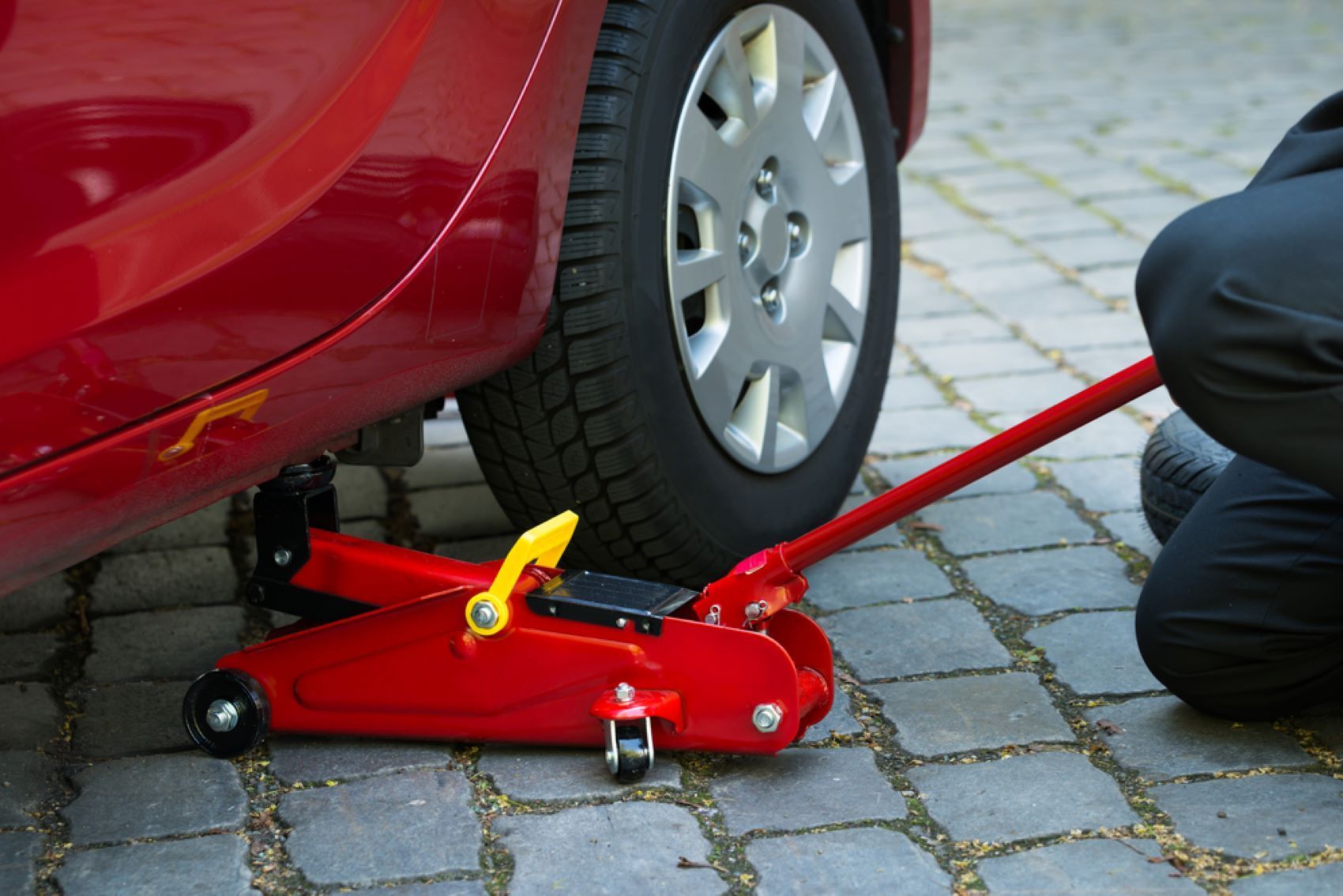 A Person is Changing a Tire on a Red Car — Alstonville Rego & Mechanical in Alstonville, NSW