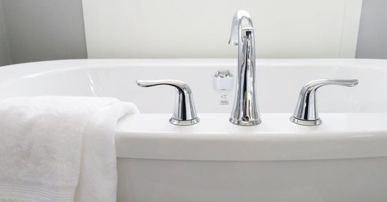 A white bathtub with chrome faucets and handles in a bathroom.