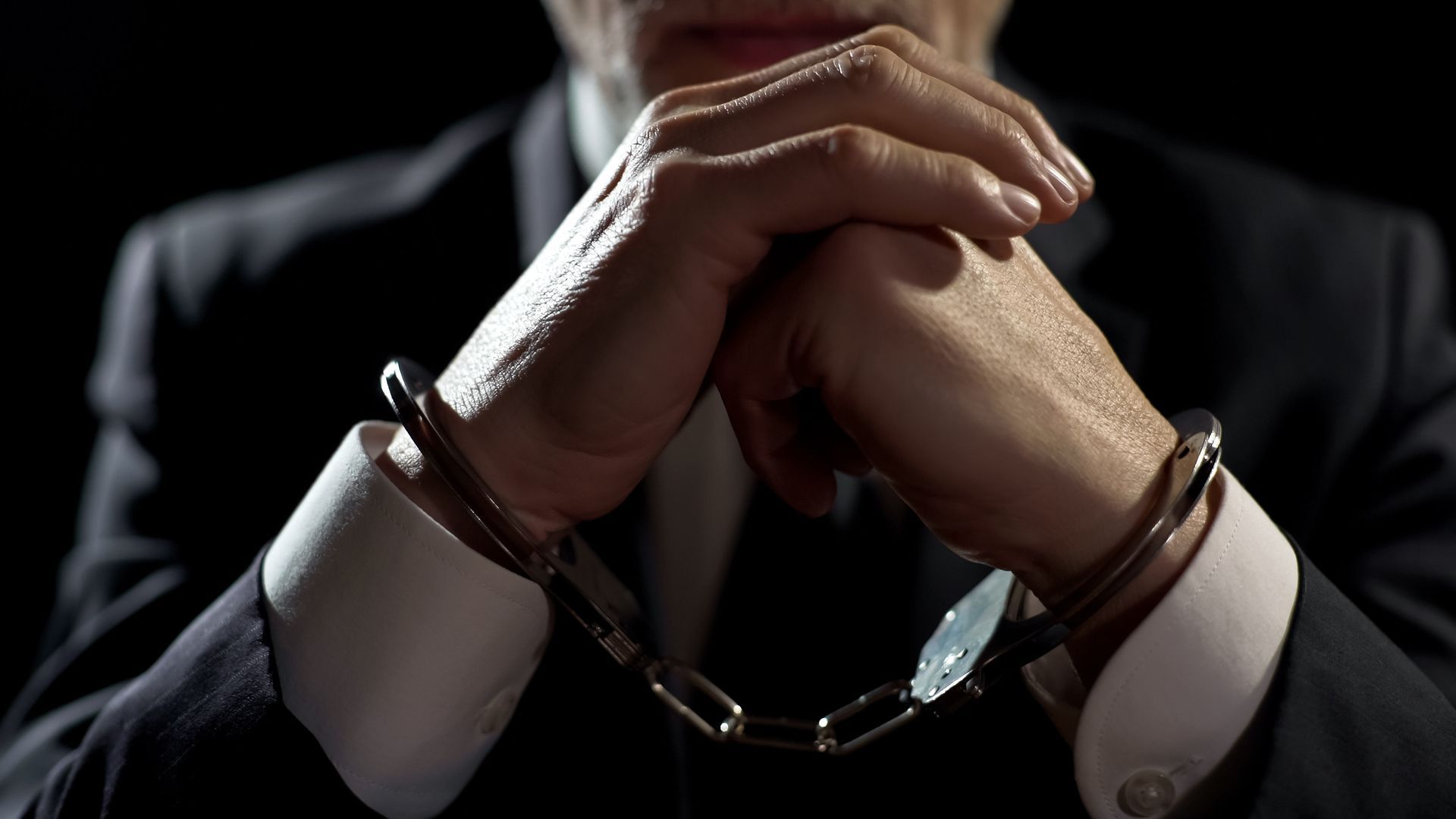 A man in a suit and tie is wearing handcuffs.