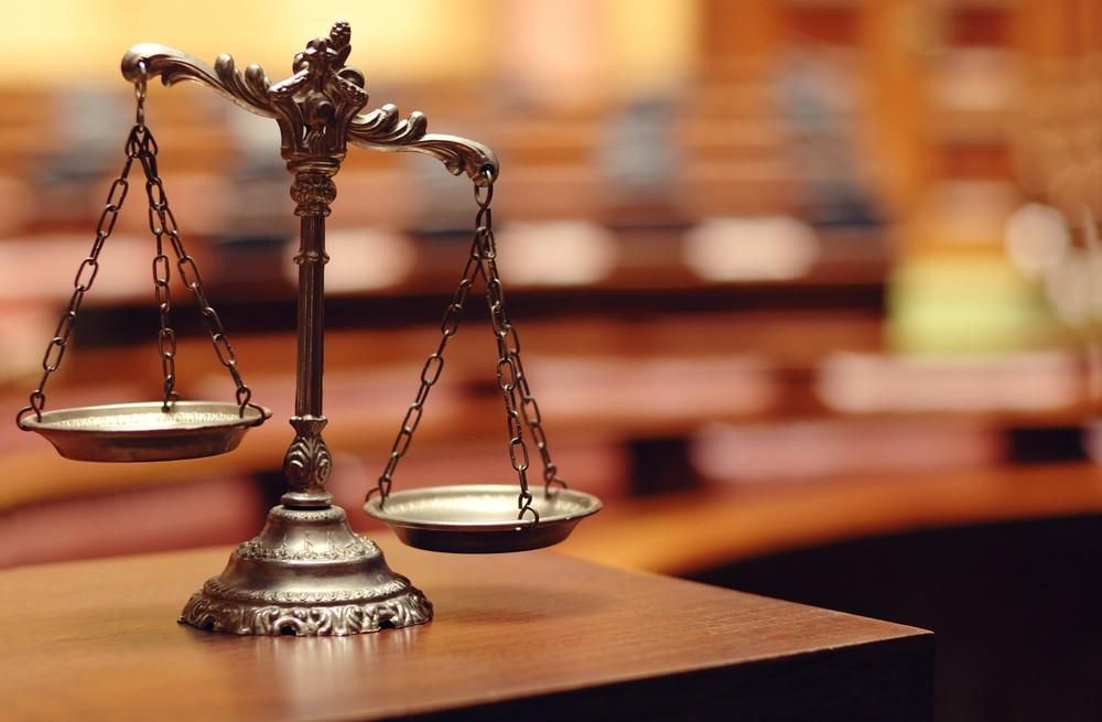A Scale of Justice is Sitting on a Wooden Table in a Courtroom — Olympus Lawyers In Ballarat Central, VIC