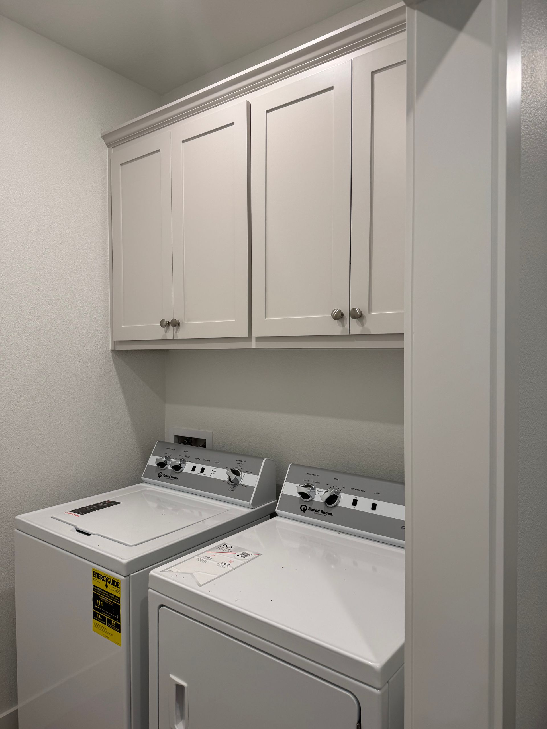 Laundry room with white cabinets above a washer and dryer.
