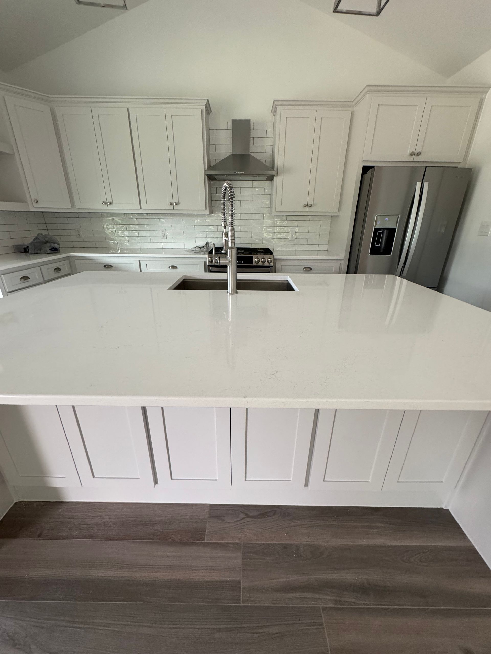 White kitchen with a large island, cabinets, and stainless steel appliances.