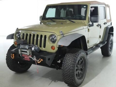 Green Jeep Wrangler with black wheels and a winch, outdoors.