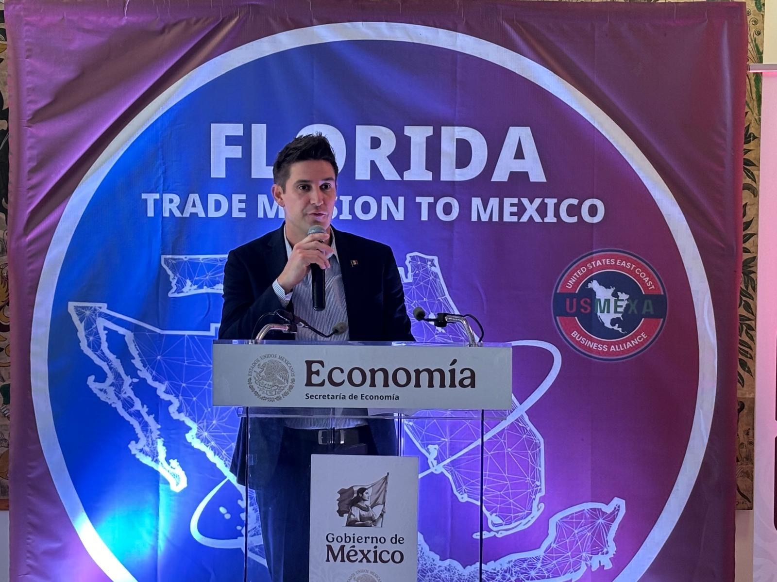 Henry Moth speaks at a podium during the Florida Trade Mission to Mexico. The backdrop features a map of Mexico and the words 