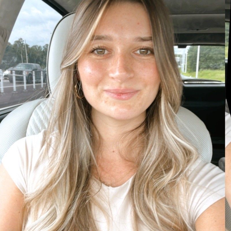 Woman with long blonde hair smiles at the camera, seated in a car, with a light-colored t-shirt.
