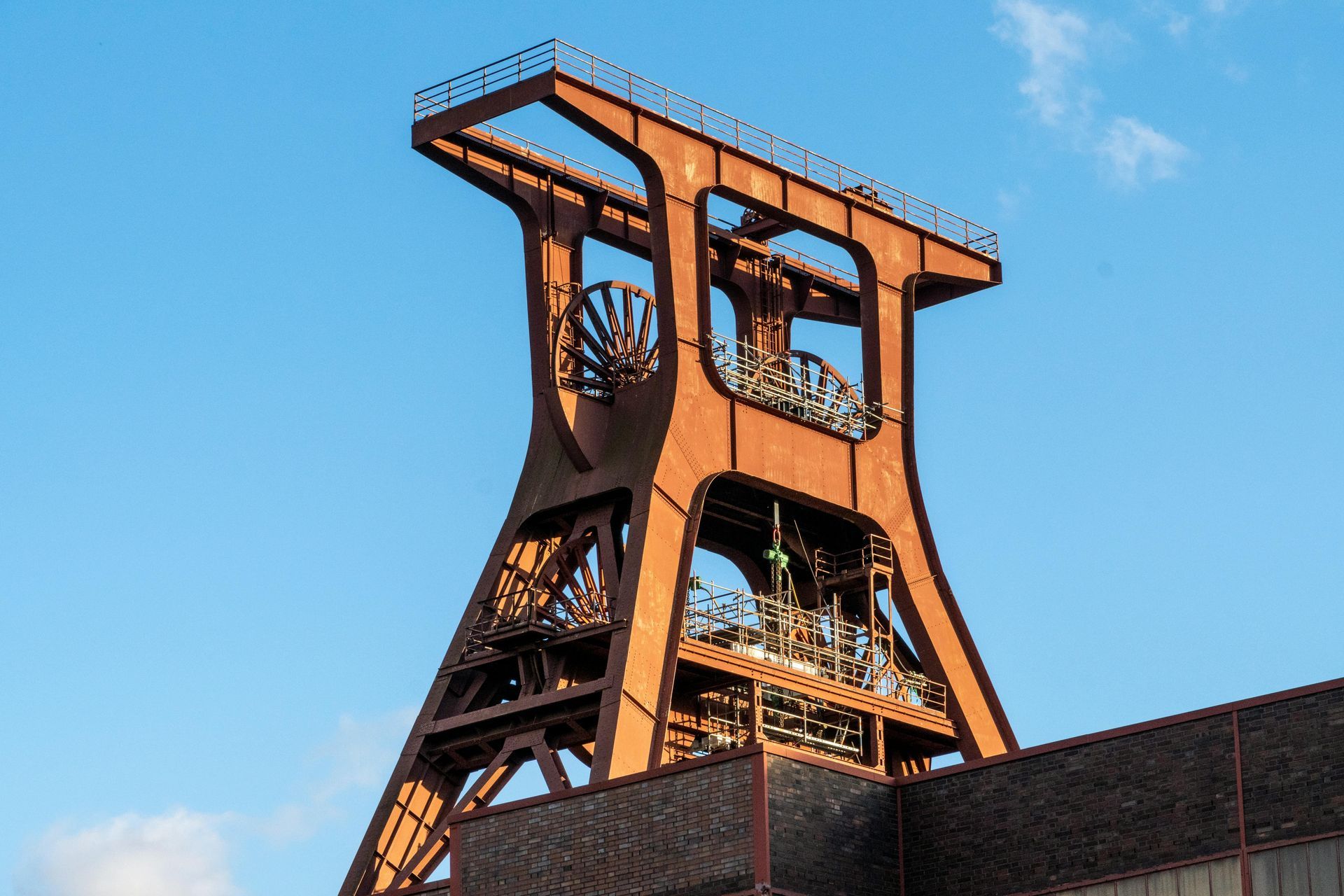 Rusty-colored industrial mine tower against a blue sky.
