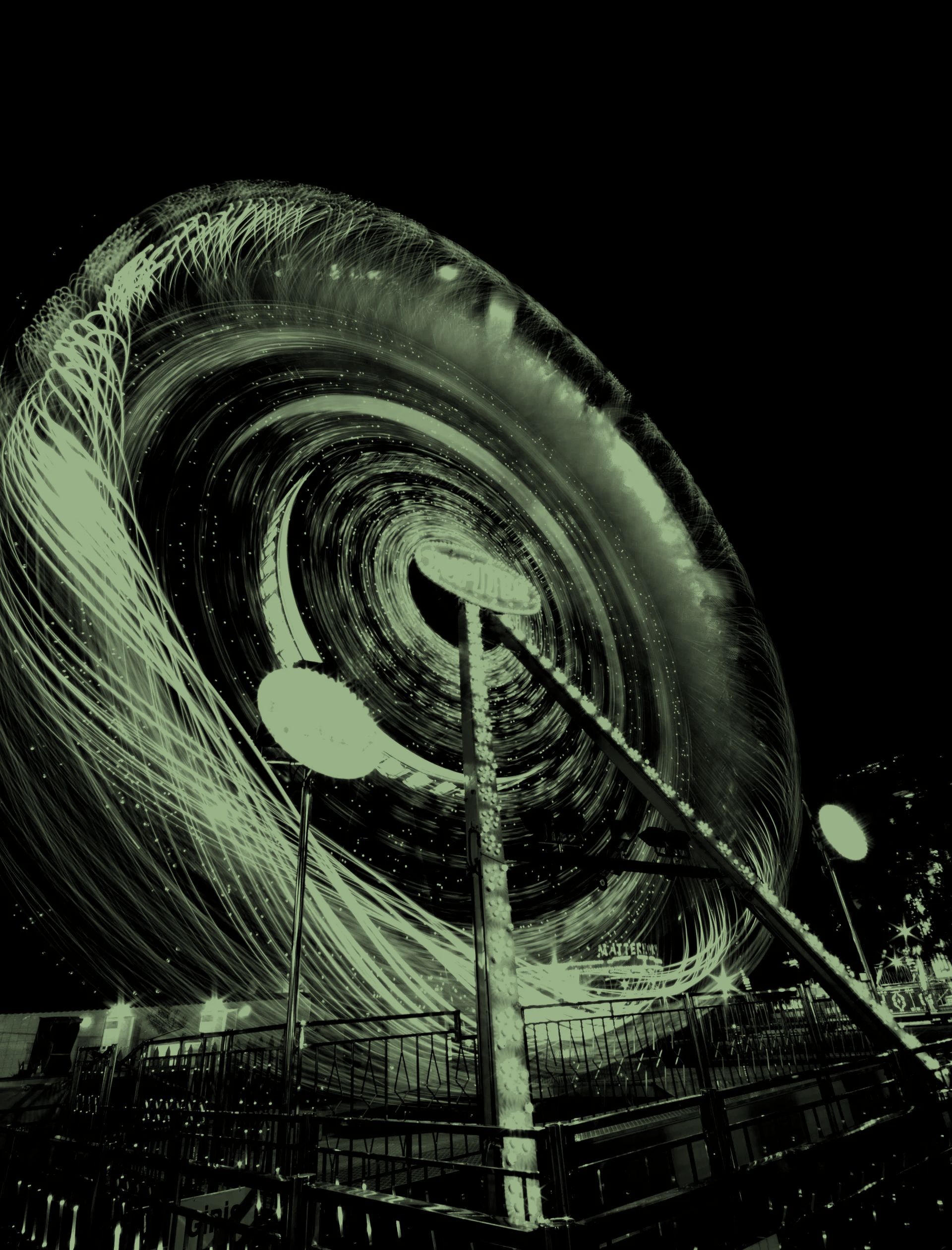 A spinning amusement park ride at night, creating light trails. Green-tinted.