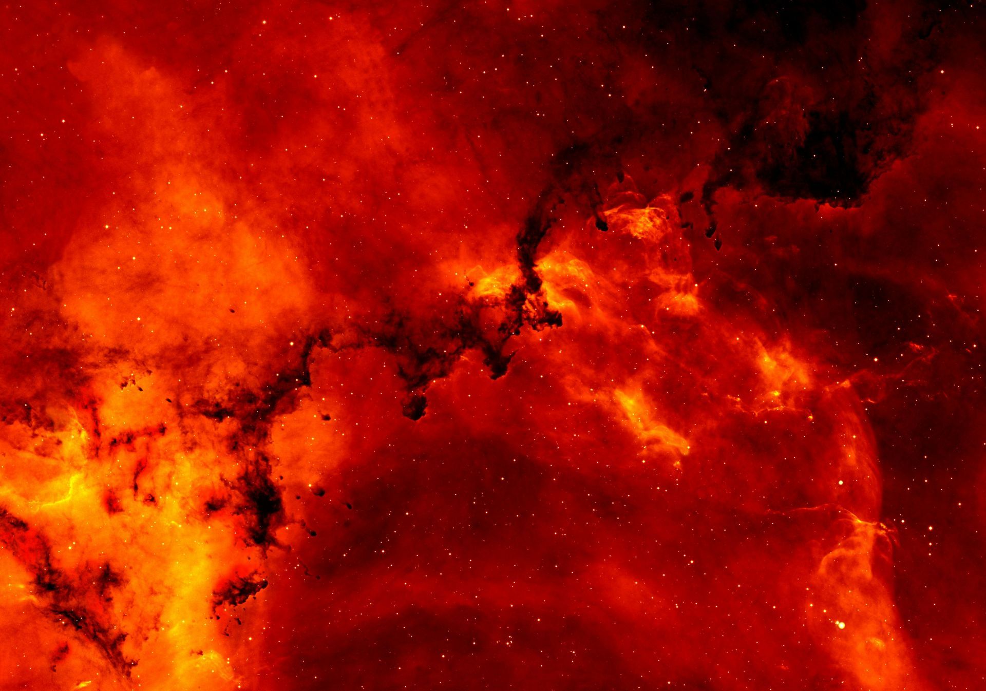 Red cosmic nebula with dark patches and scattered stars.