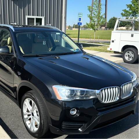 Black BMW SUV parked outside a building in daylight.