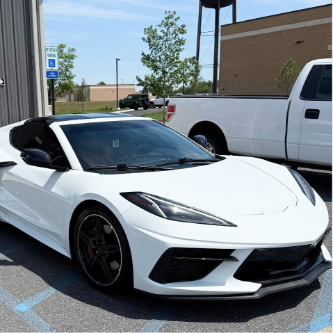 White Chevrolet Corvette parked outdoors beside a building on a sunny day