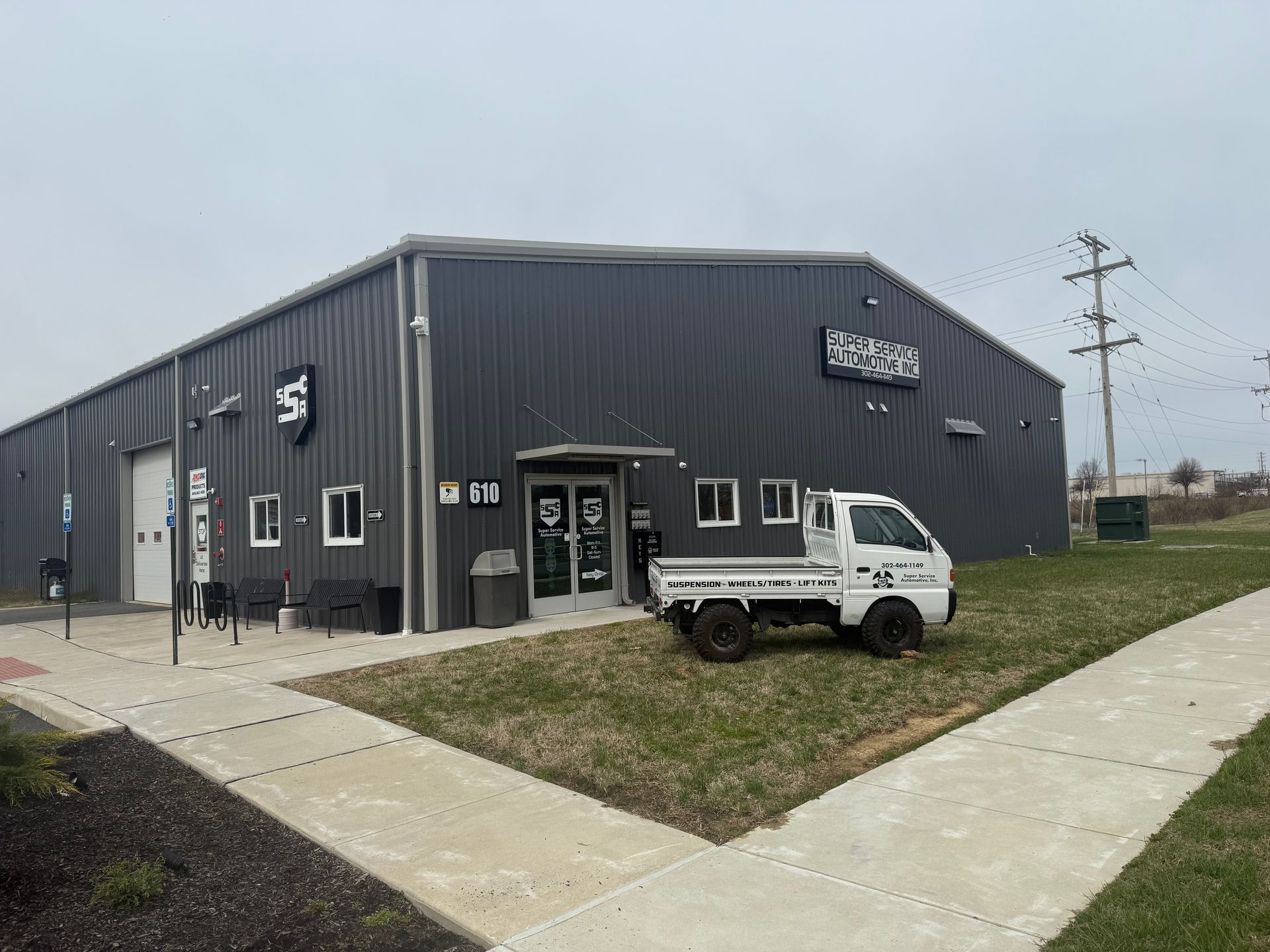 Dark gray commercial building with a white SUV parked outside on a cloudy day.